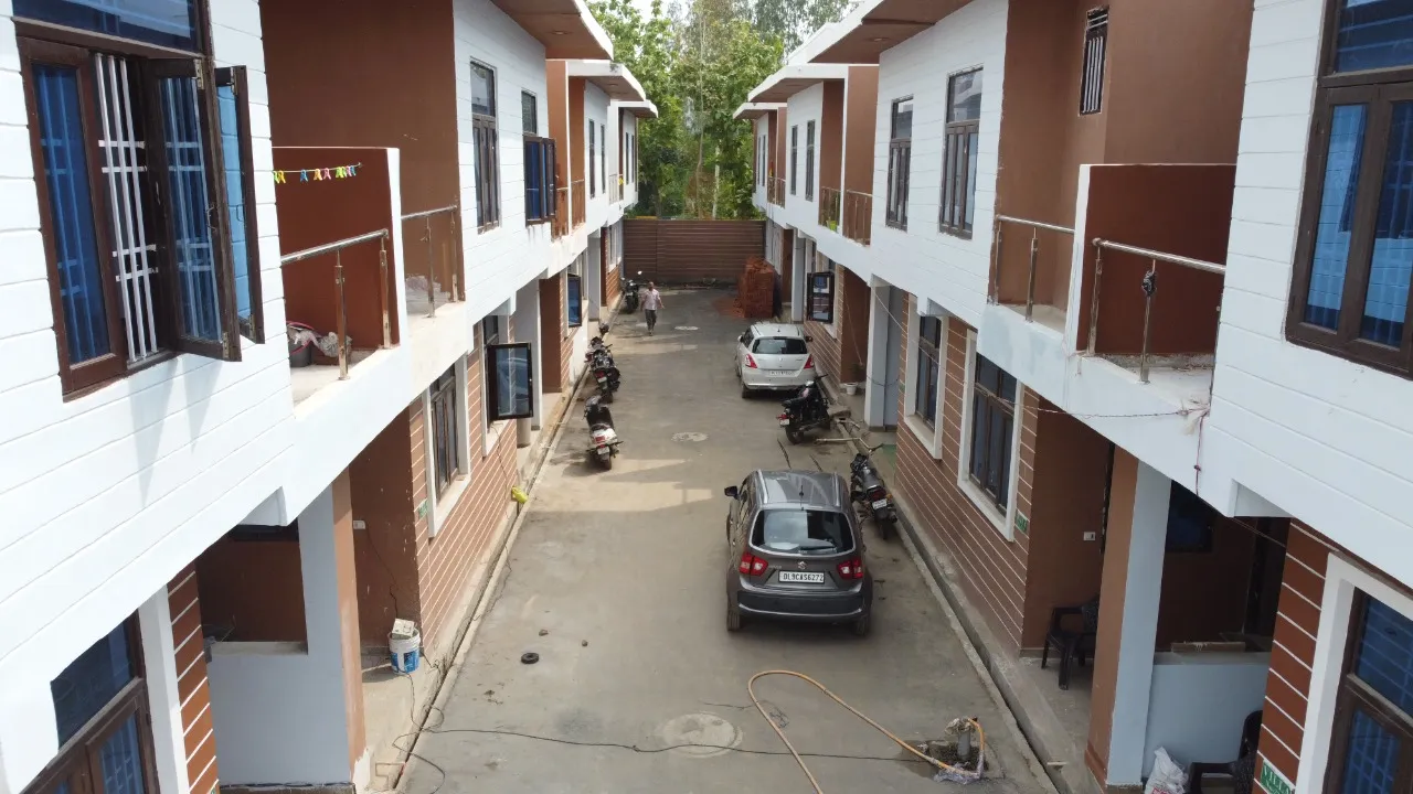 Green Villa 2 duplex villa row along the internal street in Sector 16B Noida Extension, showing balconies, parked vehicles and completed façades.